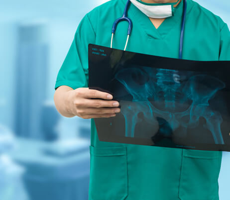 Orthopedic provider holding up diagnostic imaging to evaluate a patient for arthroscopic surgery.