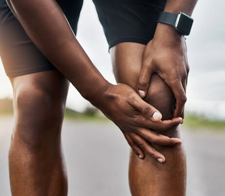 Man gripping his knee in pain who could benefit from seeing knee replacement doctors near him.