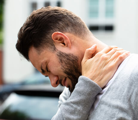 Man gripping his neck in pain in need of an appointment at a back and neck pain center.