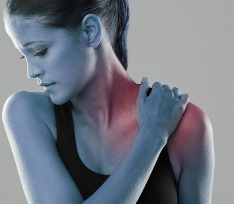 Woman holding her shoulder in pain and in need of shoulder surgery in Naples, FL.