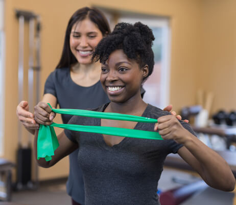 Sports medicine doctor assisting patient with a resistance band exercise.