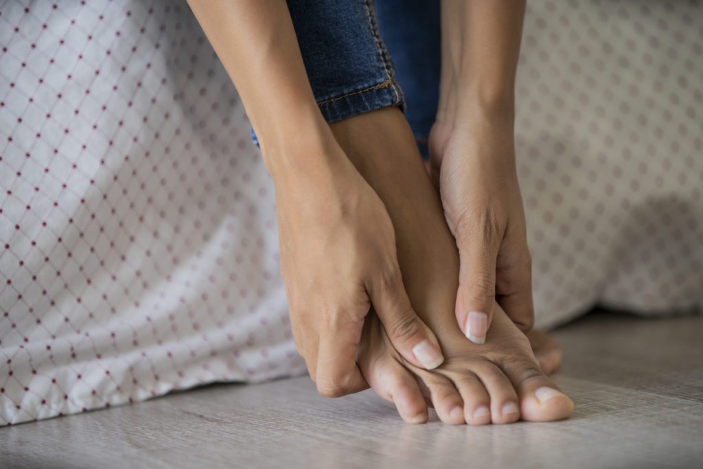 A woman rubbing her foot due to pain.