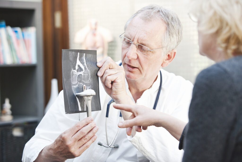 Orthopedic surgeons analysing x-ray with patient