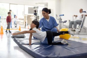 Happy girl doing stretching exercises with the help of her physiotherapist at a rehab center