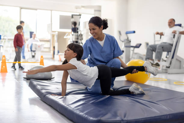 Happy girl doing stretching exercises with the help of her physiotherapist at a rehab center