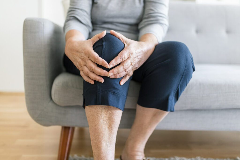 An elderly woman is holding her knee in pain due to a meniscus tear.