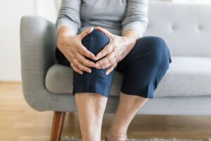 An elderly woman is holding her knee in pain due to a meniscus tear.