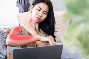 A woman is experiencing neck pain that radiates to her shoulder and down her arm, caused by excessive working on a laptop.