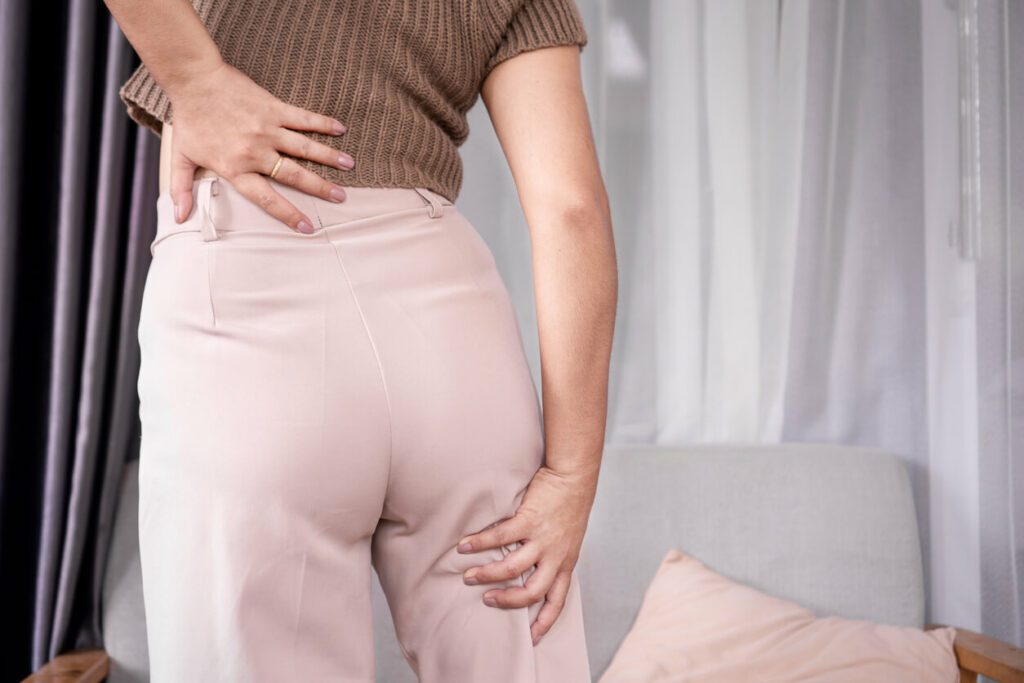 A concept of sciatica pain featuring a woman experiencing sciatic nerve pain from her lower back to her legs.