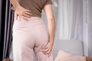 A concept of sciatica pain featuring a woman experiencing sciatic nerve pain from her lower back to her legs.