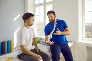 A male patient is consulting a spine specialist for physical therapy treatment of spinal stenosis, with an explanation of spine anatomy.