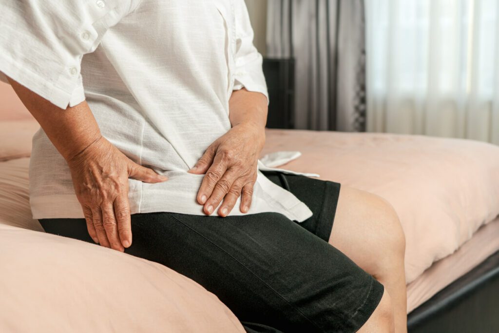 A senior woman at home is experiencing hip pain and is unsure about whether to choose hip resurfacing or total joint replacement.