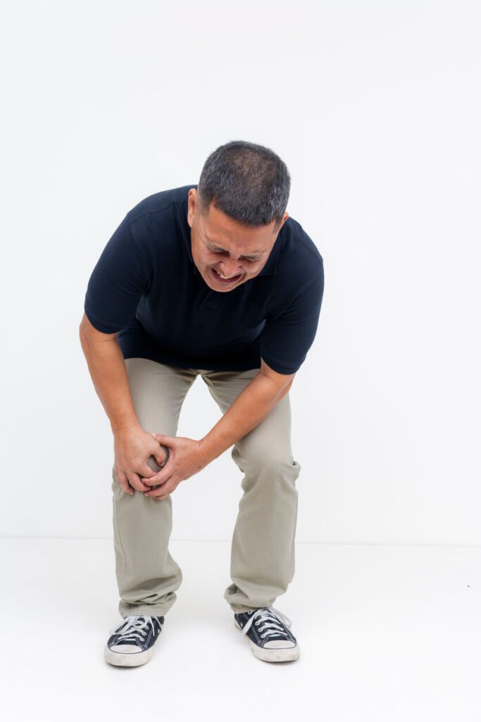 An image depicting a middle-aged man clutching his knee in severe pain, symbolizing a knee injury like a torn ACL.