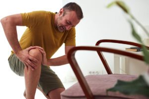 Man with painful knee caused by rheumatoid arthritis pain at home.