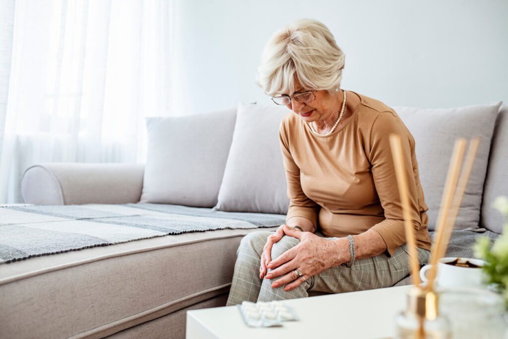 Senior woman holding the knee with Rheumatoid Arthritis pain.