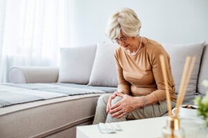 Senior woman holding the knee with Rheumatoid Arthritis pain.